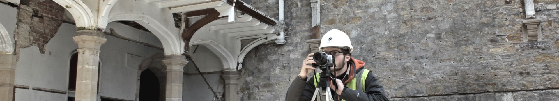 Man in hard hat viewing building through lens