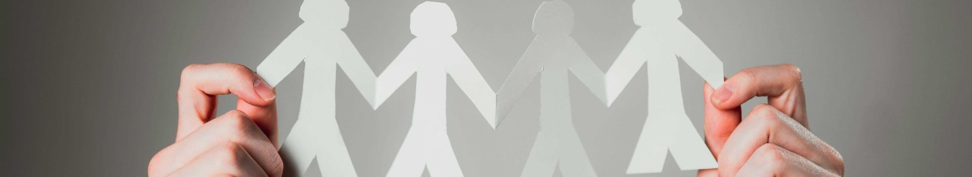 Paper cut out of people held in two hands