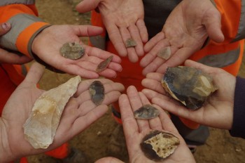 Hands in a circle hold ancient flint tools.